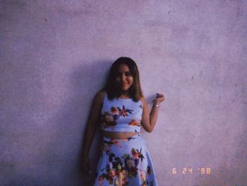 Portrait of woman standing against purple wall