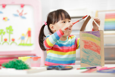 Young girl painting bird house craft at home 