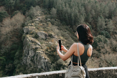 Rear view of woman sitting on rock