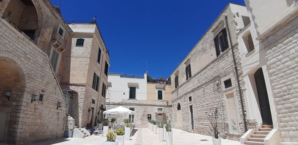 Street amidst buildings in city against clear blue sky
