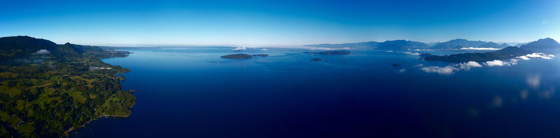 Scenic view of sea and mountains against blue sky