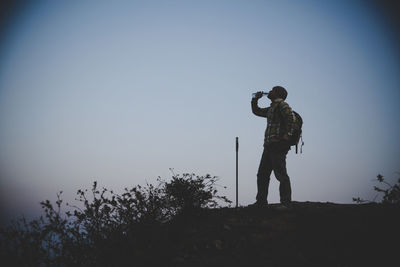 Hiker with backpack relaxing on top of a mountain and enjoying valley view during sunrise