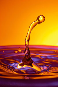 Close-up of water splashing against orange background