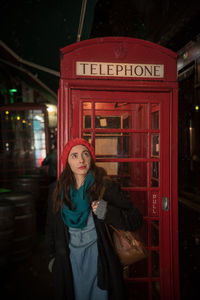 Woman standing against telephone booth