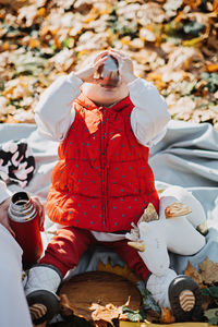 Happy little toddler baby daughter with red thermos and cup in autumn picnic in fall nature