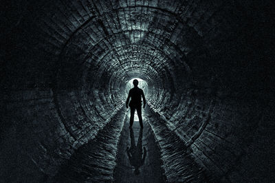 Rear view of silhouette man walking in tunnel