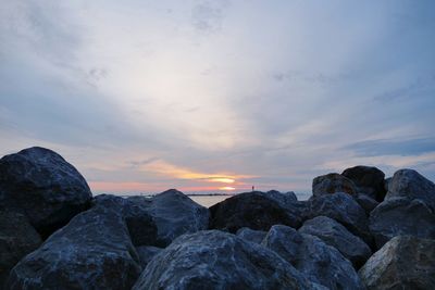 Rocks by sea against sky during sunset