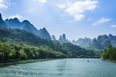 Scenic view of river by mountains against sky