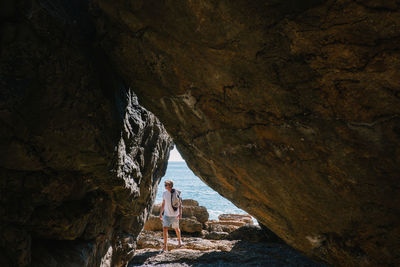 Man seen through cave standing at beach