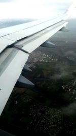 Close-up of airplane wing over cityscape