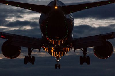 Airplane flying over lake against sky at dusk