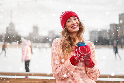 Portrait of smiling young woman wearing knit hat standing outdoors