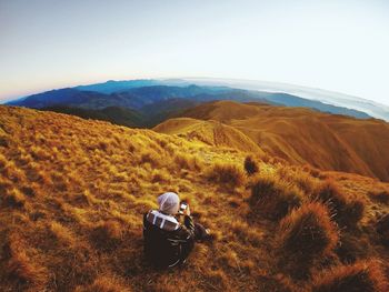 High angle view of man using phone on hill against sky