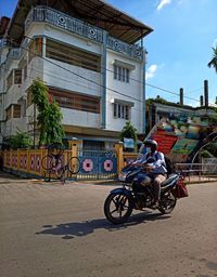 Man riding bicycle on street against buildings in city