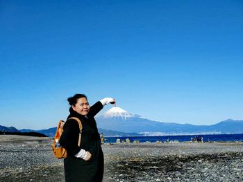 Woman pointing at mount fuji against blue sky