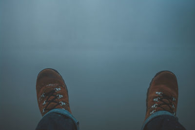 Low section of man standing against sky