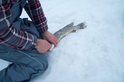 Low section of man sitting on snow