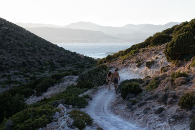 High angle view of young couple walking on dirt road against mountains