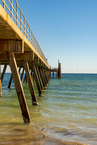 Wooden pier on sea against clear sky