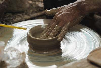 Cropped hand of man molding shape on pottery wheel