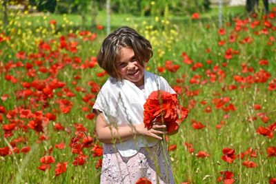 Cute girl standing on red poppy flowers