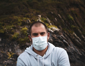 Man in mask looking at the beach looking out at the sea