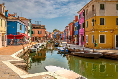 Boats moored in canal amidst buildings in city