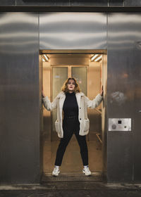 Portrait of smiling young woman standing against wall