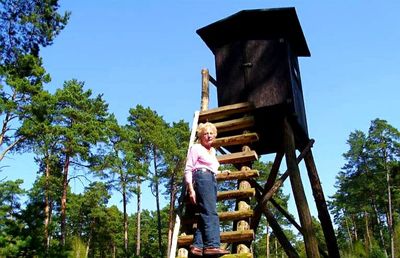 Low angle view of girl standing on ladder against sky