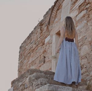 Rear view of woman standing against brick wall