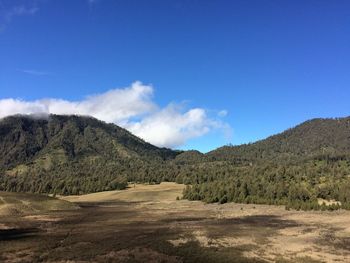 Scenic view of landscape and mountains against blue sky