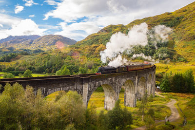 Arch bridge over mountains against sky