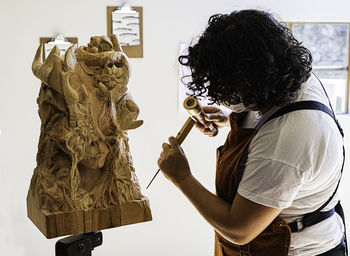 Side view of man holding sculpture