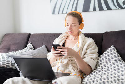 Woman using laptop while listening music at home