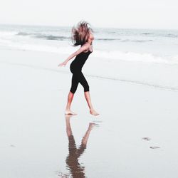 Full length of woman standing on beach against sky