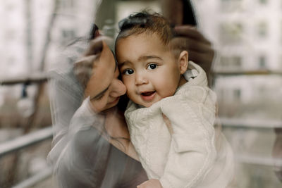 Mother carrying son seen through glass