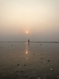 Silhouette person on beach against sky during sunset