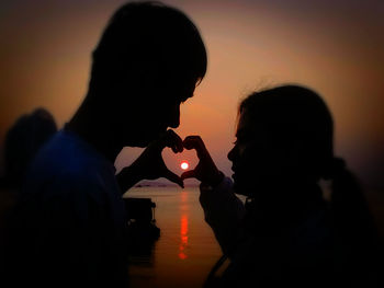 Silhouette couple with hands during sunset