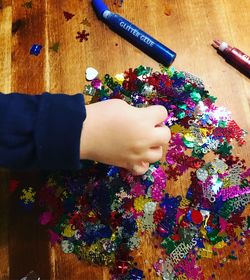 Cropped hand holding multi colored decoration on table