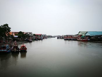 Boats moored in canal by buildings against clear sky