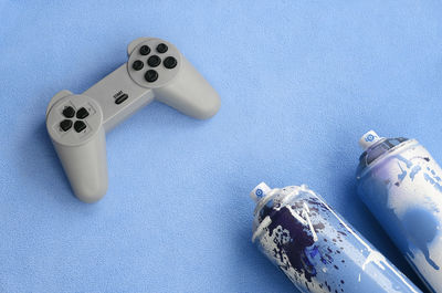 High angle view of game console and spray paint on blue background