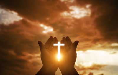 Silhouette hand against sun during sunset