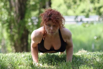 Portrait of woman doing push ups on field