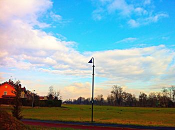 View of field against cloudy sky