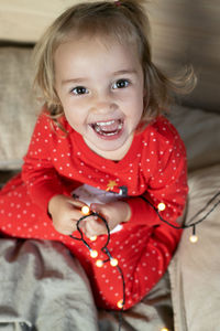 High angle view of cute baby girl sitting on bed at home