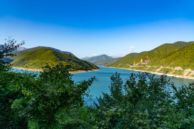 Scenic view of lake and mountains against blue sky