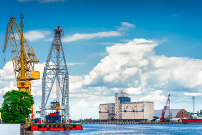 Cranes at commercial dock against sky