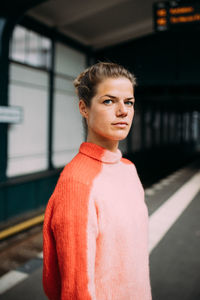 Portrait of woman standing against orange wall