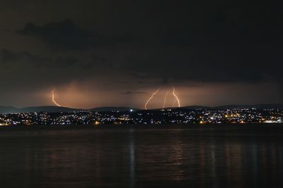 Illuminated cityscape against sky at night