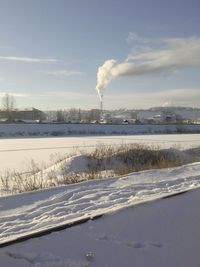 Smoke emitting from factory against sky